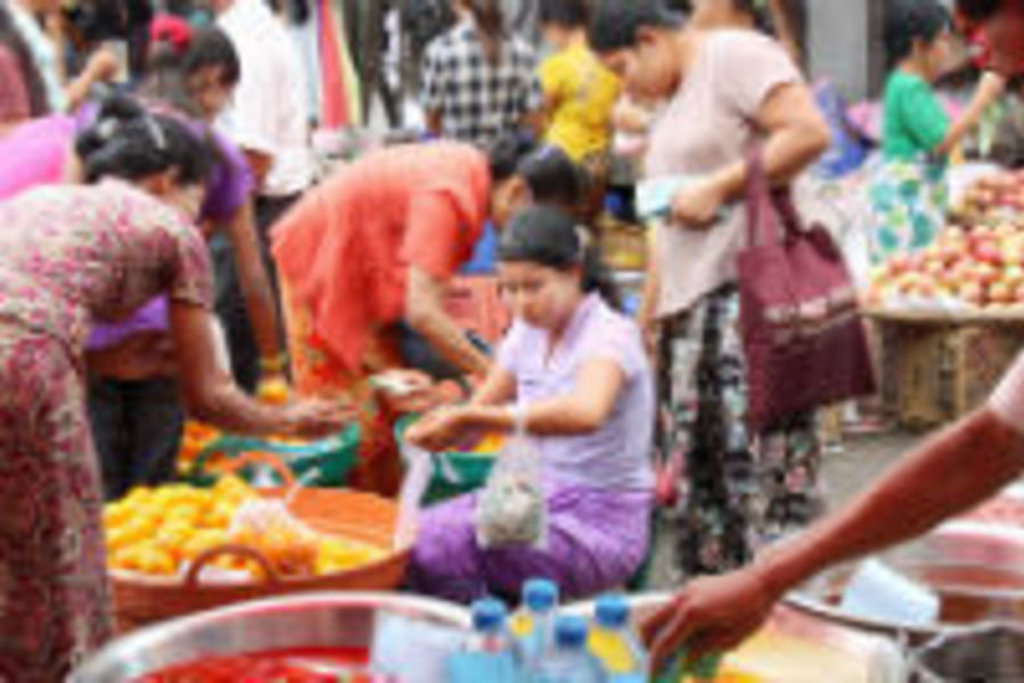Drukke markt in Myanmar met locals die groenten en fruit verkopen tijdens een groepsrondreis langs hoogtepunten.