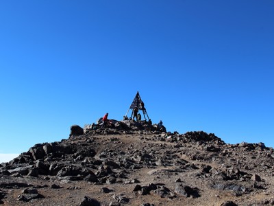 Bergwandelaars bij het topbord op de top van de Mt. Toubkal tijdens de beklimmingsroute.