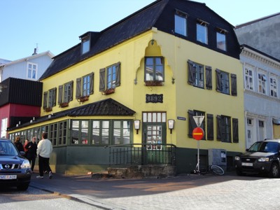 Geel historisch gebouw met zwarte luiken in Reykjavik, IJsland.