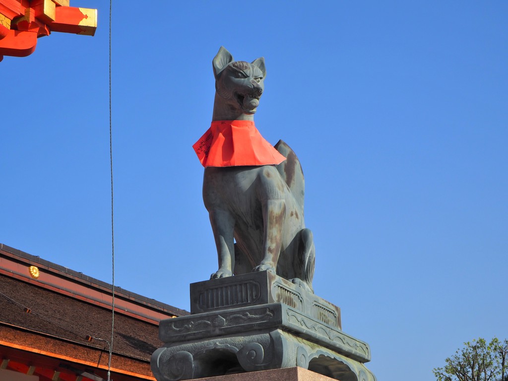 Vosbeeld bij Fushimi Inari-schrijn in Kyoto, Japan, met rood slabbetje tegen een blauwe lucht.