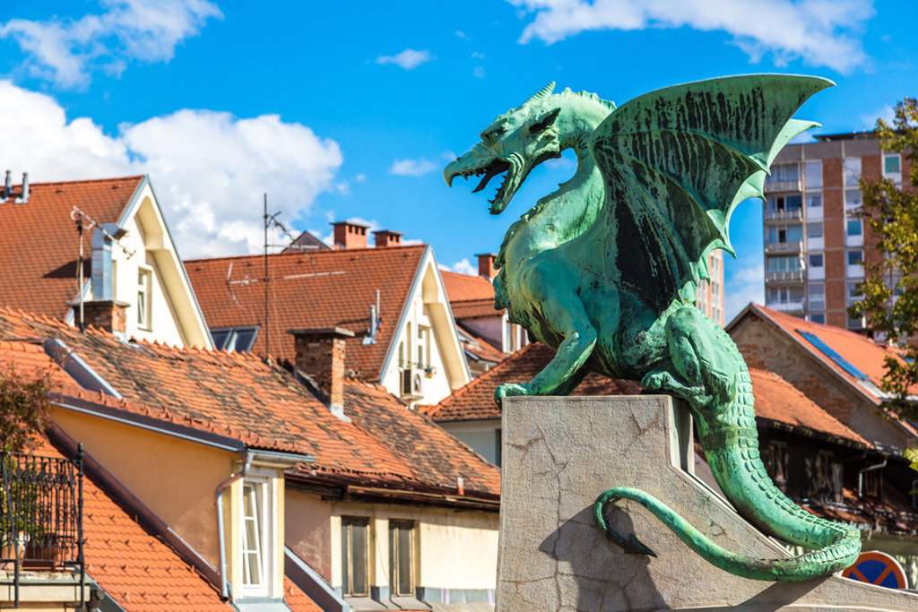 Draakbeeld op de Drakenbrug in Ljubljana, Slovenië, met rode daken op de achtergrond.