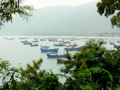 Vissersboten in de baai bij Quy Nhon, Vietnam, met bergen op de achtergrond.