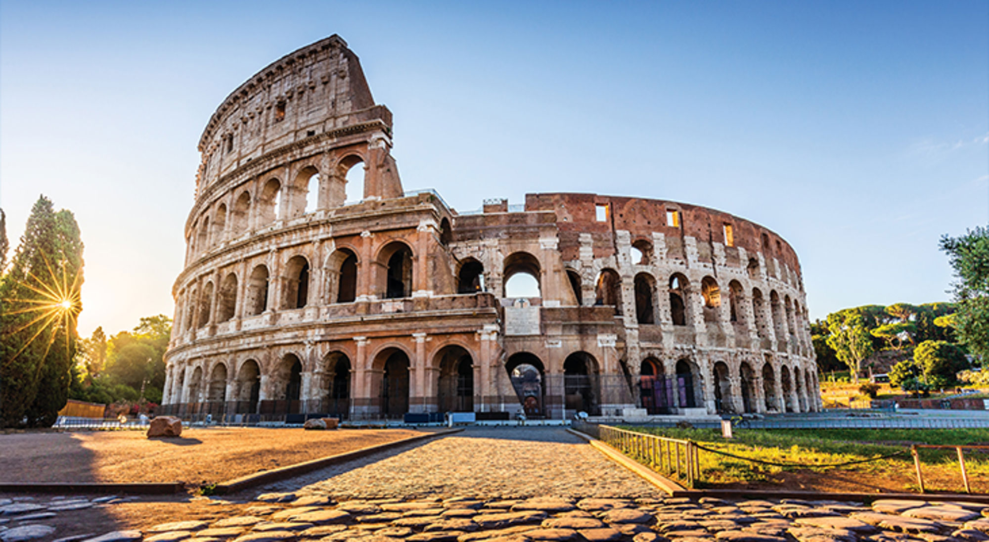 Het Colosseum in Rome - 7 nieuwe wereldwonderen Colosseum in Rome bij zonsopkomst, met het amfitheater in de ochtendzon en een heldere blauwe lucht.