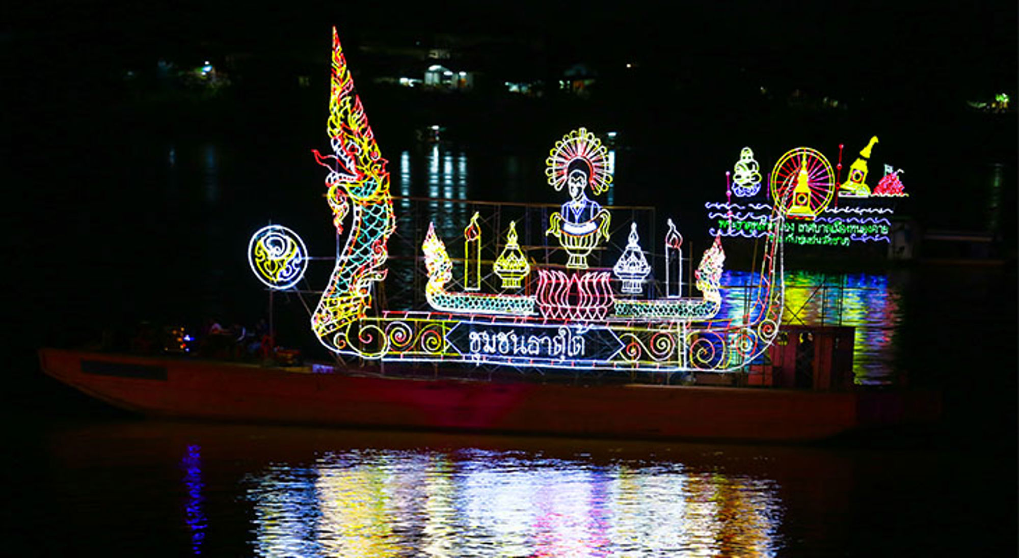 Verlichte boot tijdens Wan Ok Phansa in Thailand Verlichte boot met kleurrijke lichtkunst op het water tijdens een nachtelijk festival.