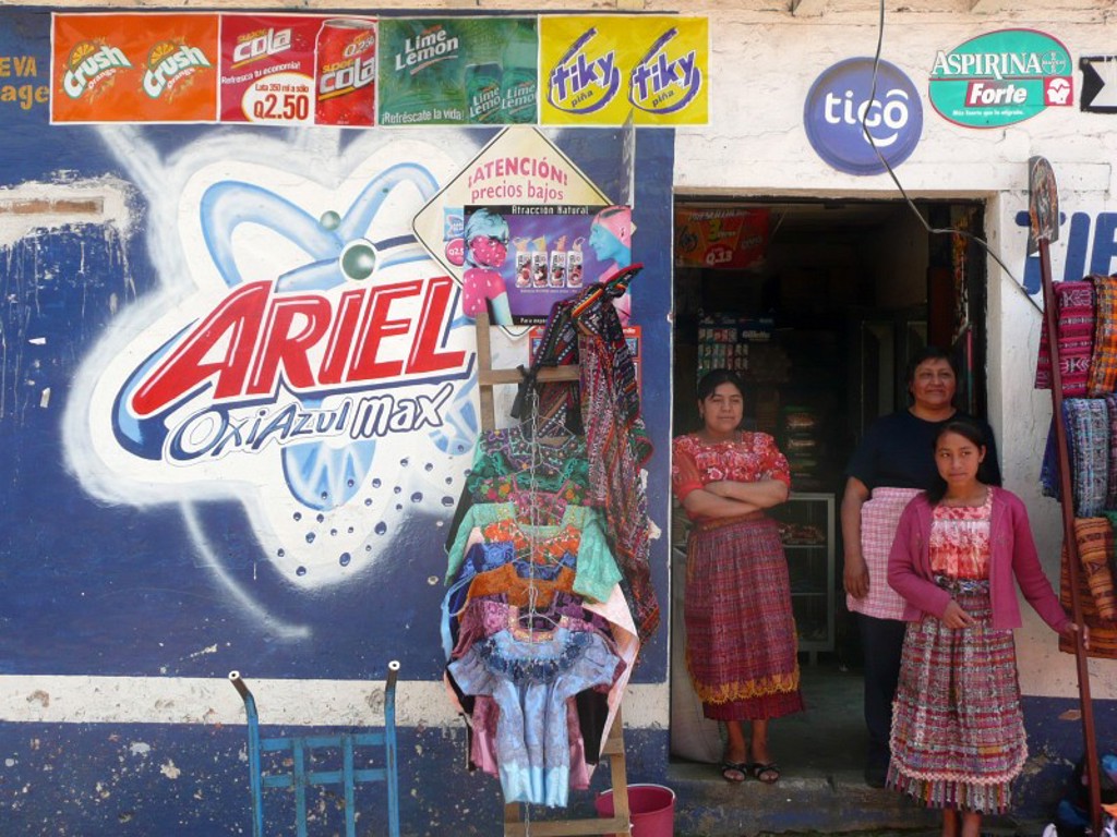 Vrouwen voor een lokale winkel met kleurrijke textiel in Guatemala tijdens groepsrondreis Mexico, Guatemala en Honduras.