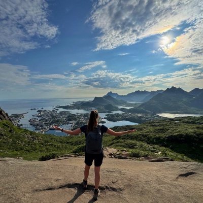 Wandelaar met rugzak kijkt uit over fjorden en bergen in Noorwegen tijdens een groepsrondreis.