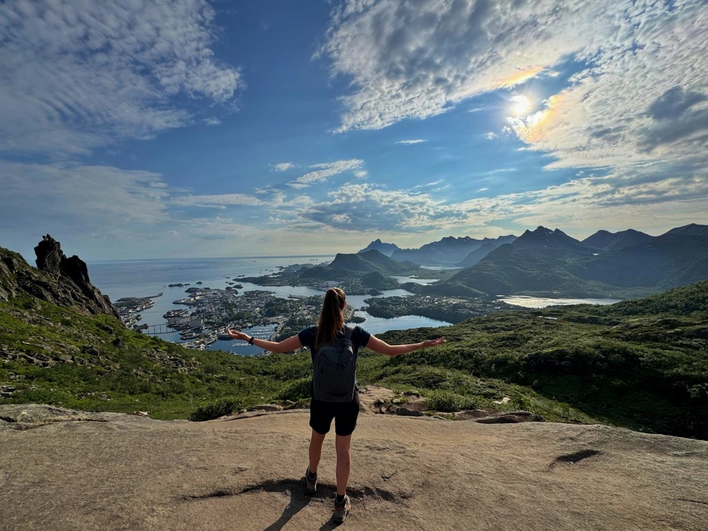 Wandelaar met rugzak kijkt uit over fjorden en bergen in Noorwegen tijdens een groepsrondreis.