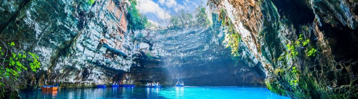 Turquoise ondergronds meer in de Melissani Cave op Kefalonia, met bootjes onder een open grotkoepel.