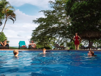 Reizigers ontspannen in een zwembad met ligbedden onder palmbomen tijdens de Route Costa Rica, dag 12.