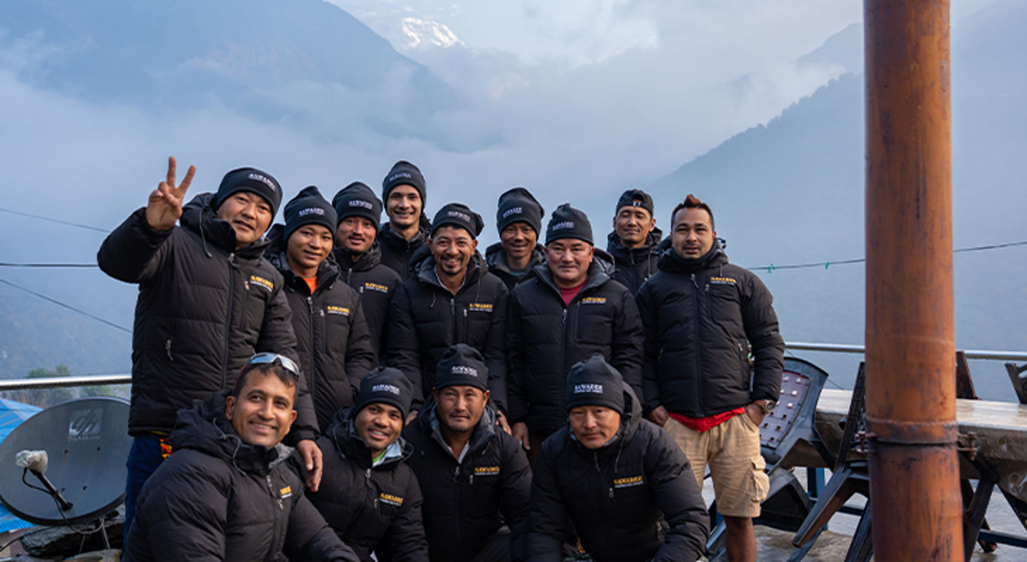 Dragers trekking Nepal Groepsfoto van berggidsen in warme jassen met mistige bergen op de achtergrond.