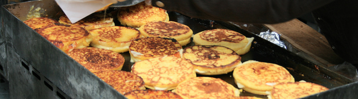 Traditionele Colombiaanse arepas worden gebakken op een hete bakplaat op een markt.