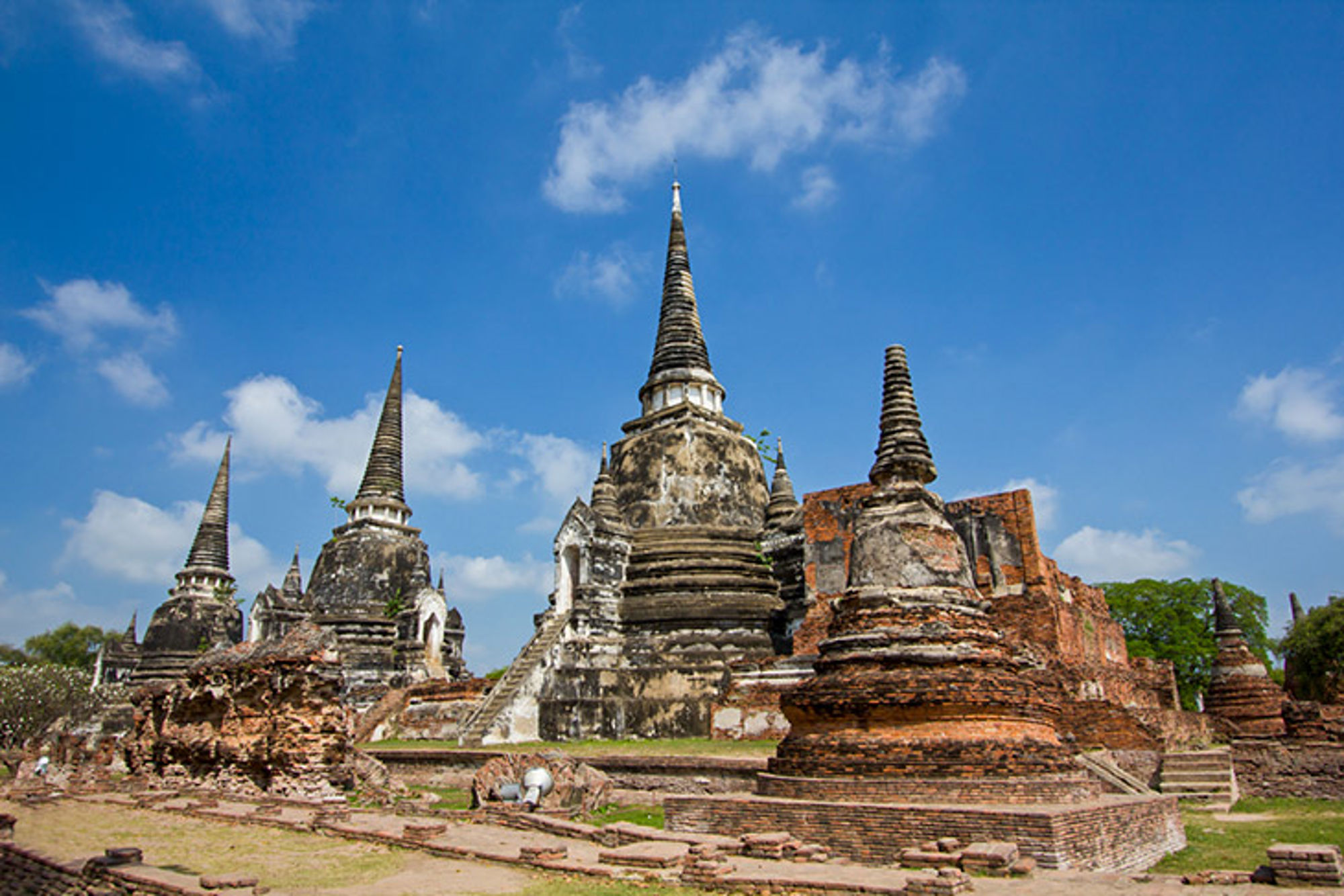 Oude tempels in Thailand Oude tempelruïnes met chedi’s in Ayutthaya, Thailand, onder een blauwe lucht.
