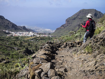 Wandelaar op bergpad met uitzicht op een vallei en kustlijn tijdens de wandelvakantie Tenerife & La Palma.