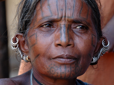 Portret van vrouw met traditionele gezichtstatoeages en zilveren oorsieraden in Odisha, tijdens Route Orissa 23 dagen.