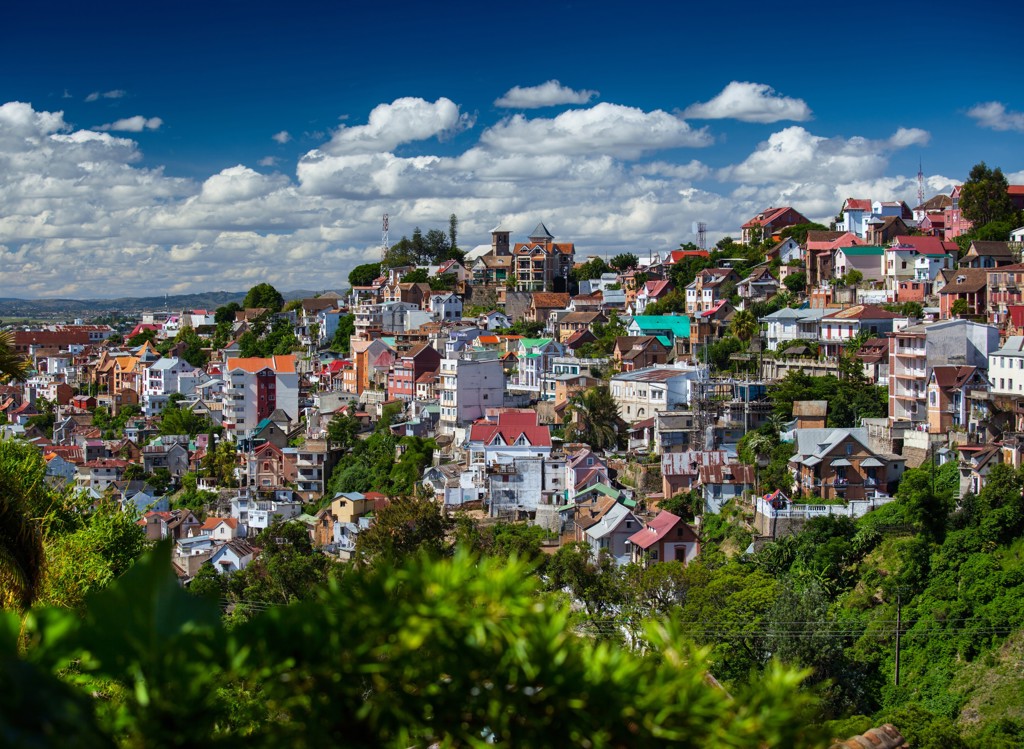 Uitzicht over kleurrijke huizen op de heuvels van Antananarivo, Madagascar, onder een blauwe lucht met wolken.
