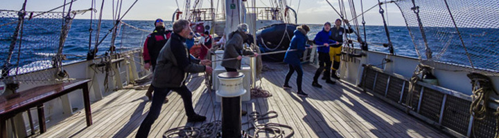 Reizigers hijsen zeilen op een zeilschip op zee richting het ijzige Spitsbergen.