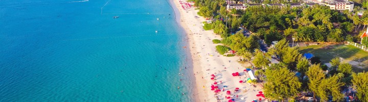 Patong Beach in Thailand met turkooisblauw water, wit zandstrand en rode parasols.