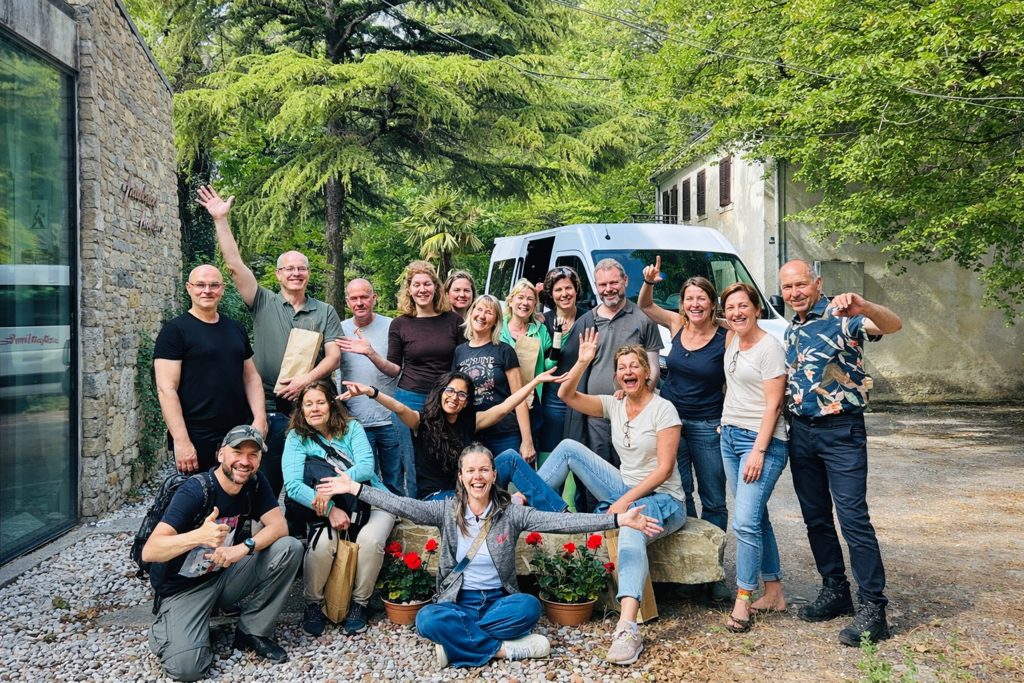 Groepsfoto van reizigers tijdens een groepsrondreis in Slovenië, bij een bus in een groene omgeving.