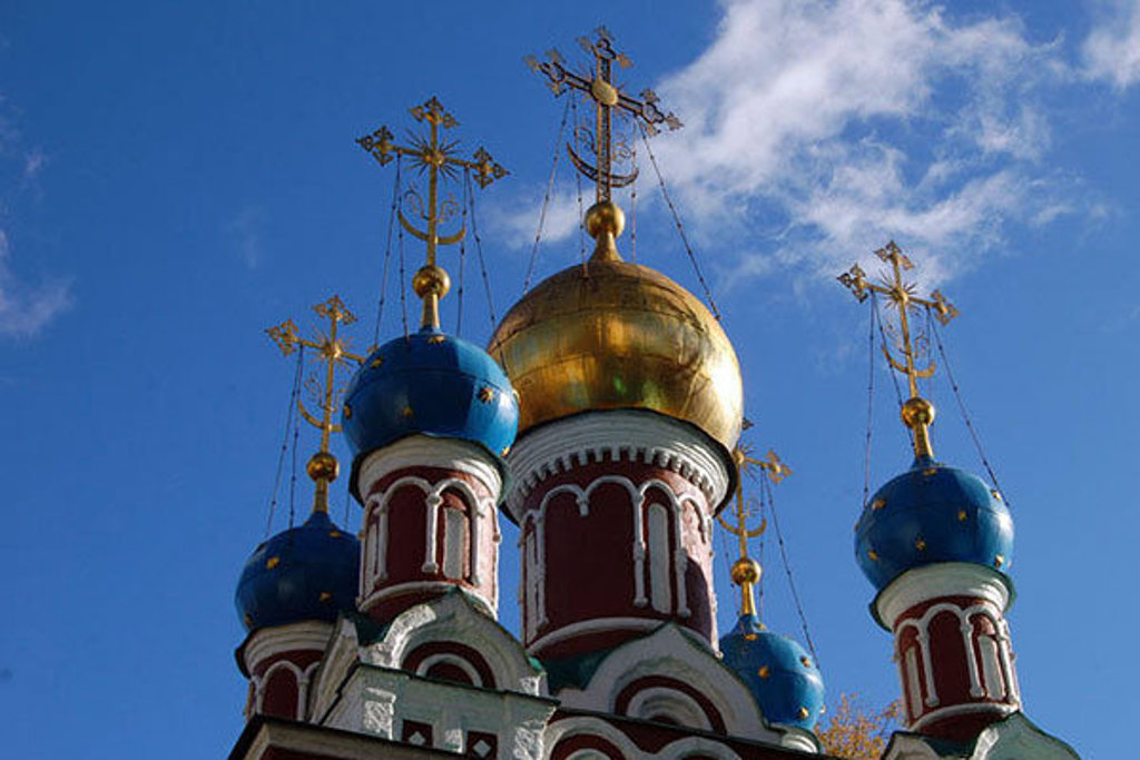 Gouden en blauwe koepels van een Russisch-orthodoxe kerk onder een heldere winterlucht in Rusland.
