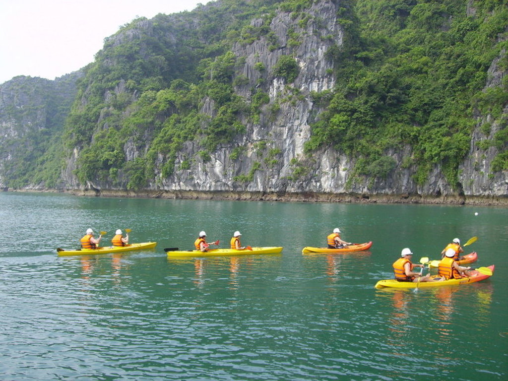 Kajakken in Halong Bay tijdens een familiereis Vietnam, met kalkstenen kliffen op de achtergrond.