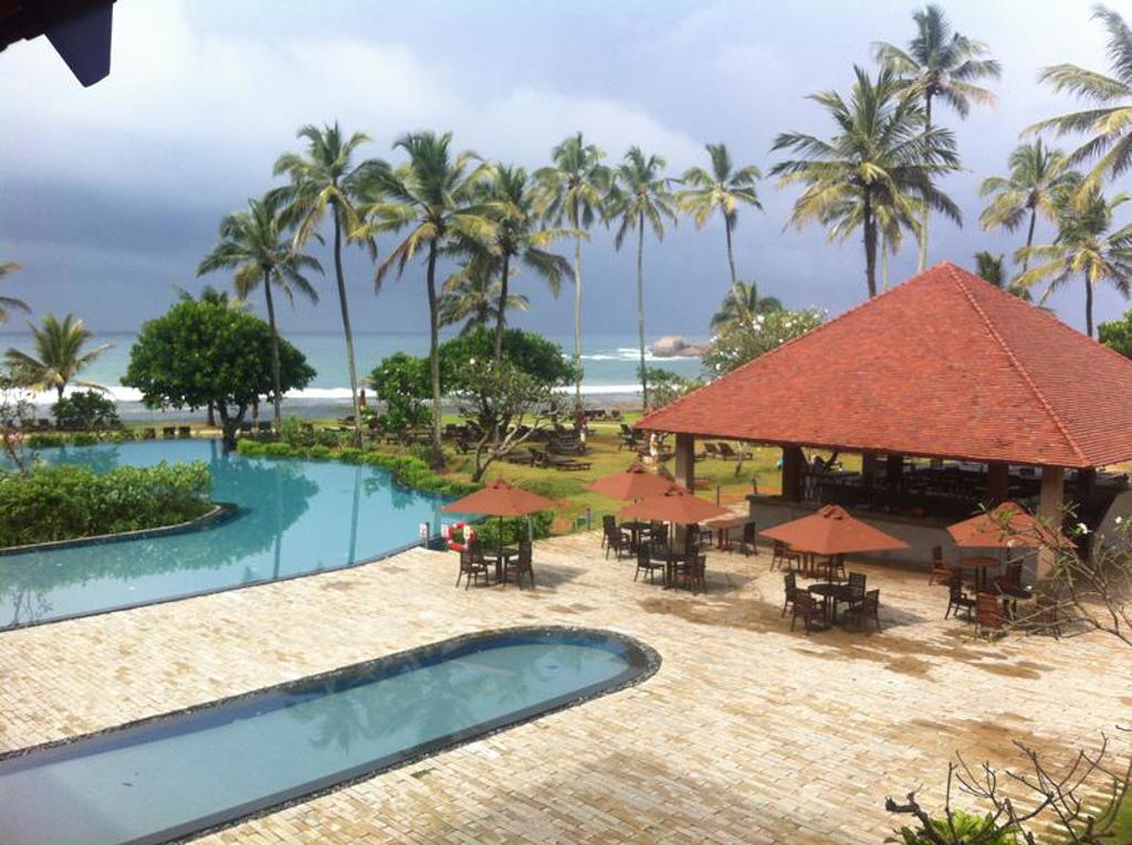 Zwembad bij strandresort met palmbomen en terras, tijdens familiereis Sri Lanka hoogtepunten.