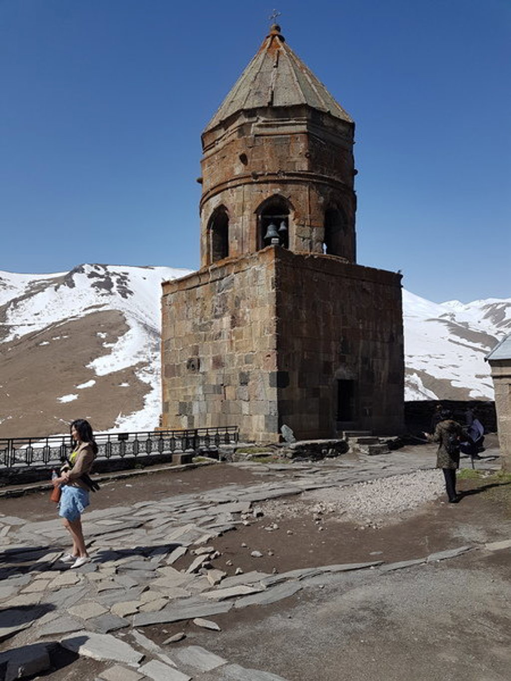 Gergeti Drievuldigheidskerk bij Kazbegi in Georgië, met besneeuwde bergen op de achtergrond.