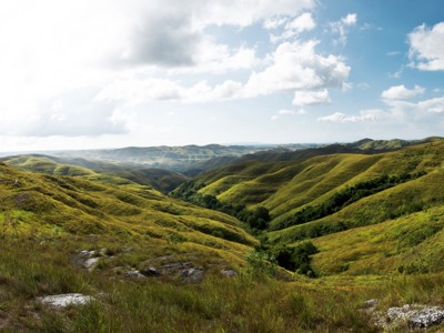 Groene heuvels en valleien op Sumba onder een dramatische wolkenlucht tijdens de route Timor, Sumba & Bali.