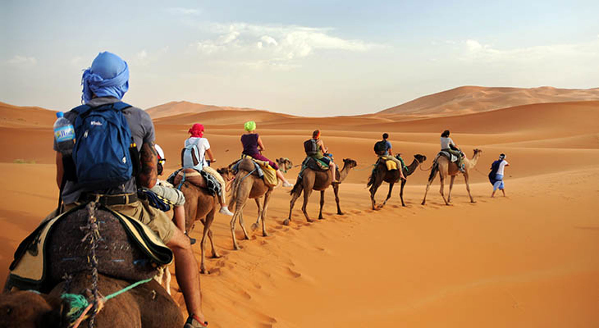 Sahara Marokko Karavaan met toeristen op kamelen door de zandduinen van de Sahara in Marokko.