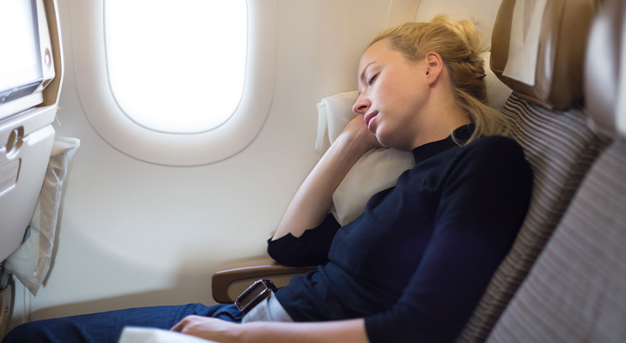 Slapen in het vliegtuig Slapende passagier bij het raam in een vliegtuigstoel tijdens een vlucht.