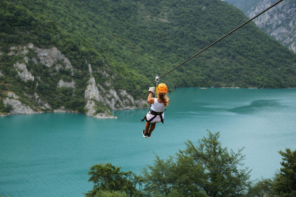 Kind aan de zipline boven een turquoise bergmeer tijdens de familiereis Zuid-Oost Europa.