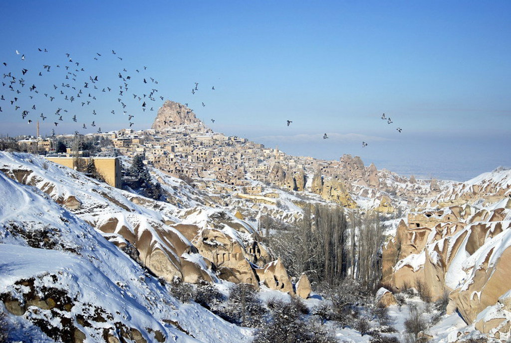 Sneeuwlandschap met rotsformaties en dorp in Cappadocië, Turkije, tijdens een wandelvakantie.