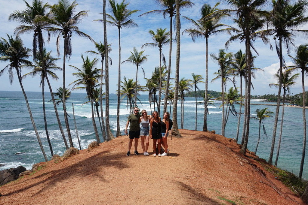 Groep reizigers bij palmbomen aan de kust tijdens een fietsvakantie in Sri Lanka.