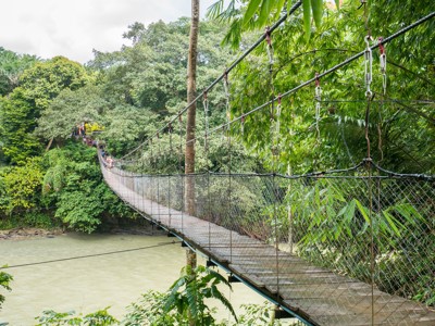 Hangbrug over een rivier in het regenwoud op de route Sumatra, Java en Bali.