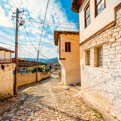 Kasseienstraat met traditionele huizen in een historisch dorp in Albanië tijdens familiereis.