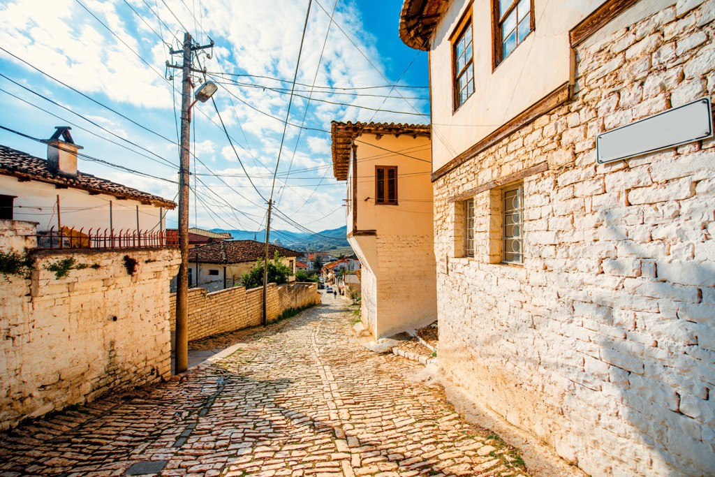 Kasseienstraat met traditionele huizen in een historisch dorp in Albanië tijdens familiereis.