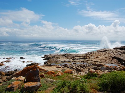 Rotsachtige kust met golven en opspattend zeewater langs de Tuinroute in Zuid-Afrika.