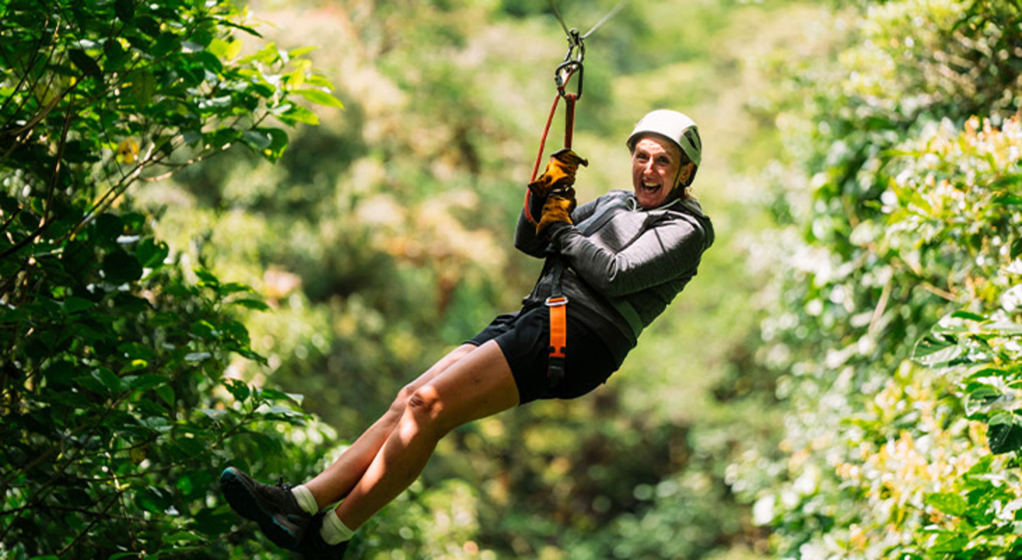 Reiziger aan een zipline door het groen tijdens een Sawadee groepsreis.