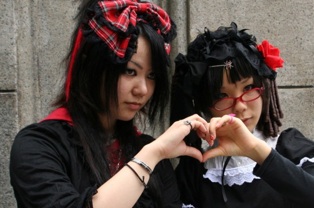 Twee jongeren in gothic lolita-stijl maken een hartje met hun handen tijdens een groepsrondreis Japan.