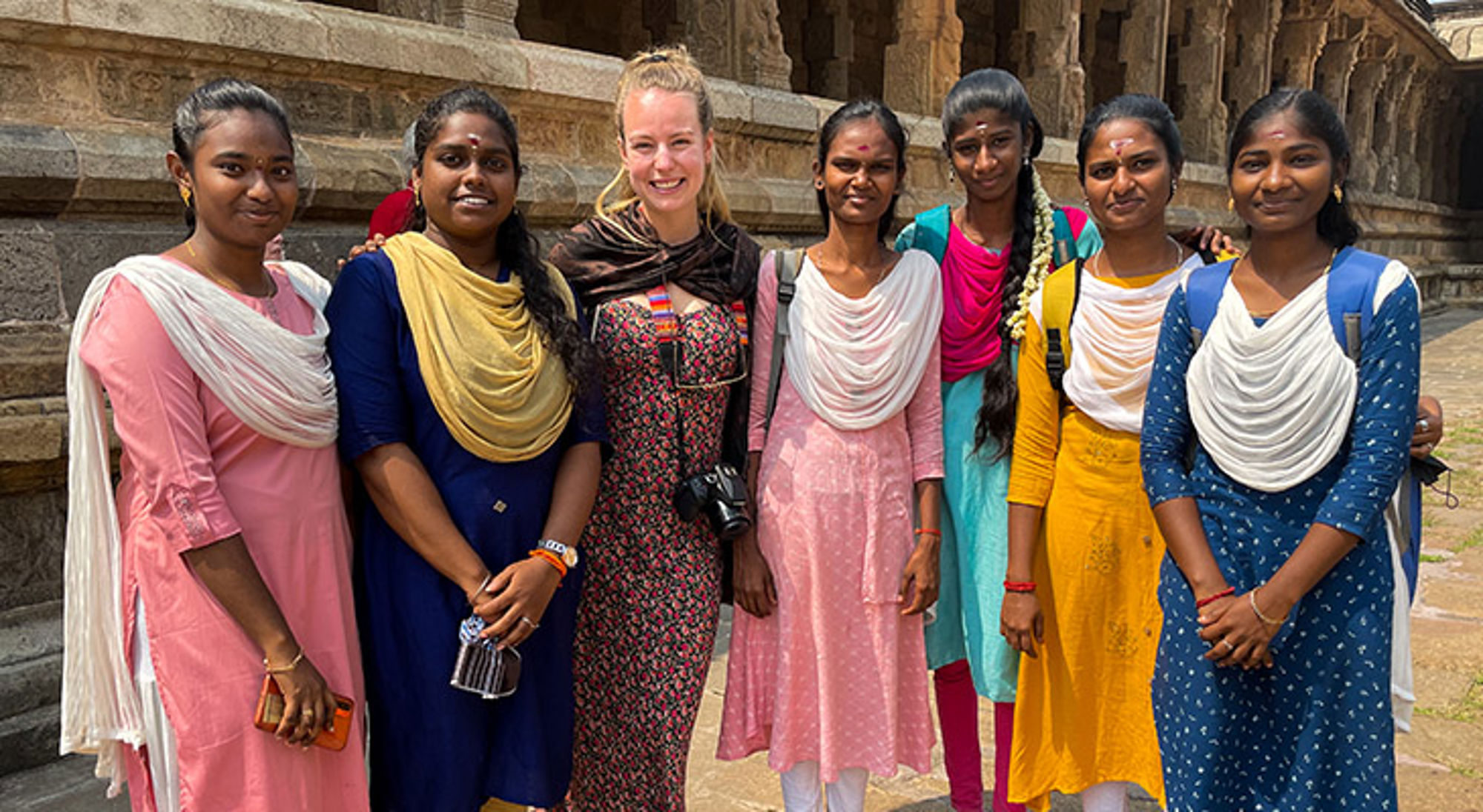 Respecteer de lokale cultuur en tradities Groep vrouwen poseert bij een historische tempel, gekleed in kleurrijke traditionele kleding.
