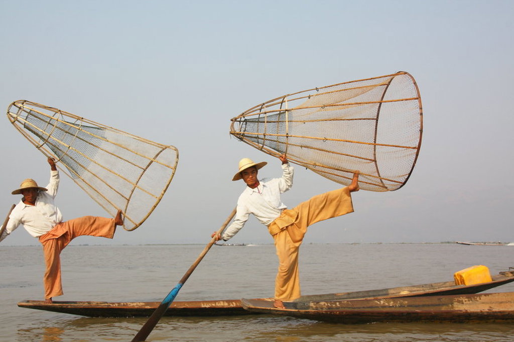 Vissers op Inle Lake in Myanmar balanceren op een boot met grote visnetten.