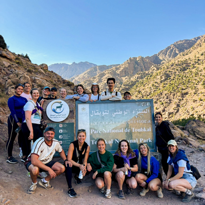 Groep 22-35ers reizigers bij het bord van Parc National de Toubkal in het Atlasgebergte, Marokko.