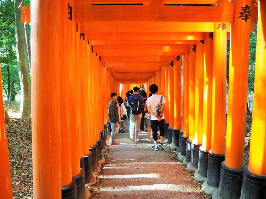 Reizigers lopen door de rode torii-poorten bij Fushimi Inari-taisha in Kyoto, Japan.