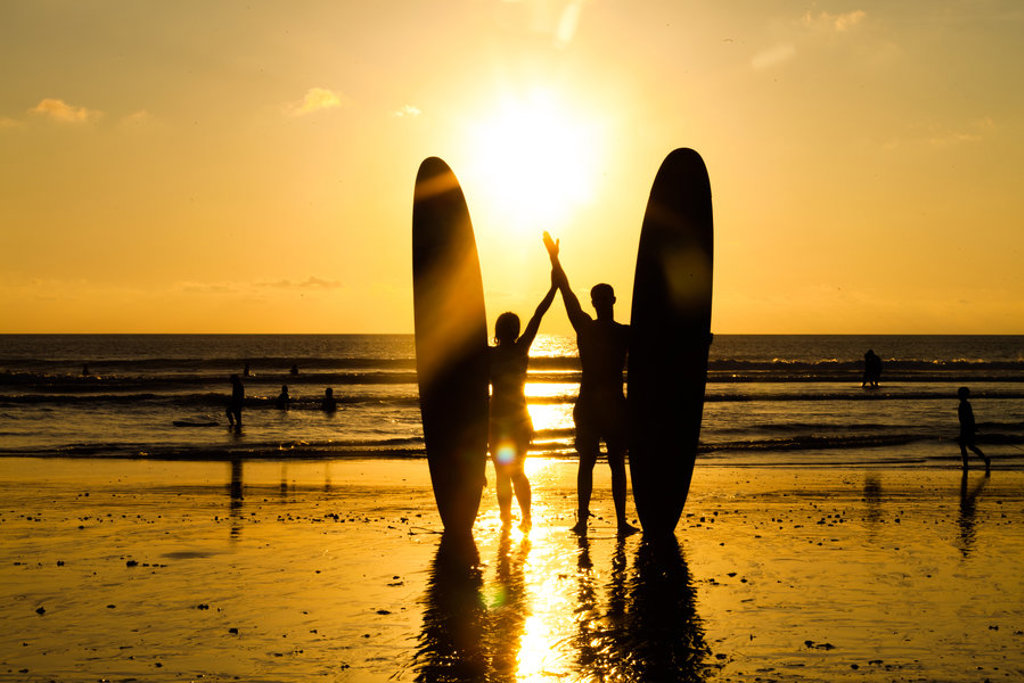Twee surfers met surfplanken op het strand bij zonsondergang op Bali, Indonesië.