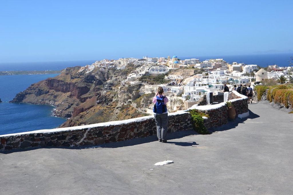 Wandelaars met uitzicht op de witte huizen en kliffen van Santorini tijdens wandelvakantie in Griekenland.