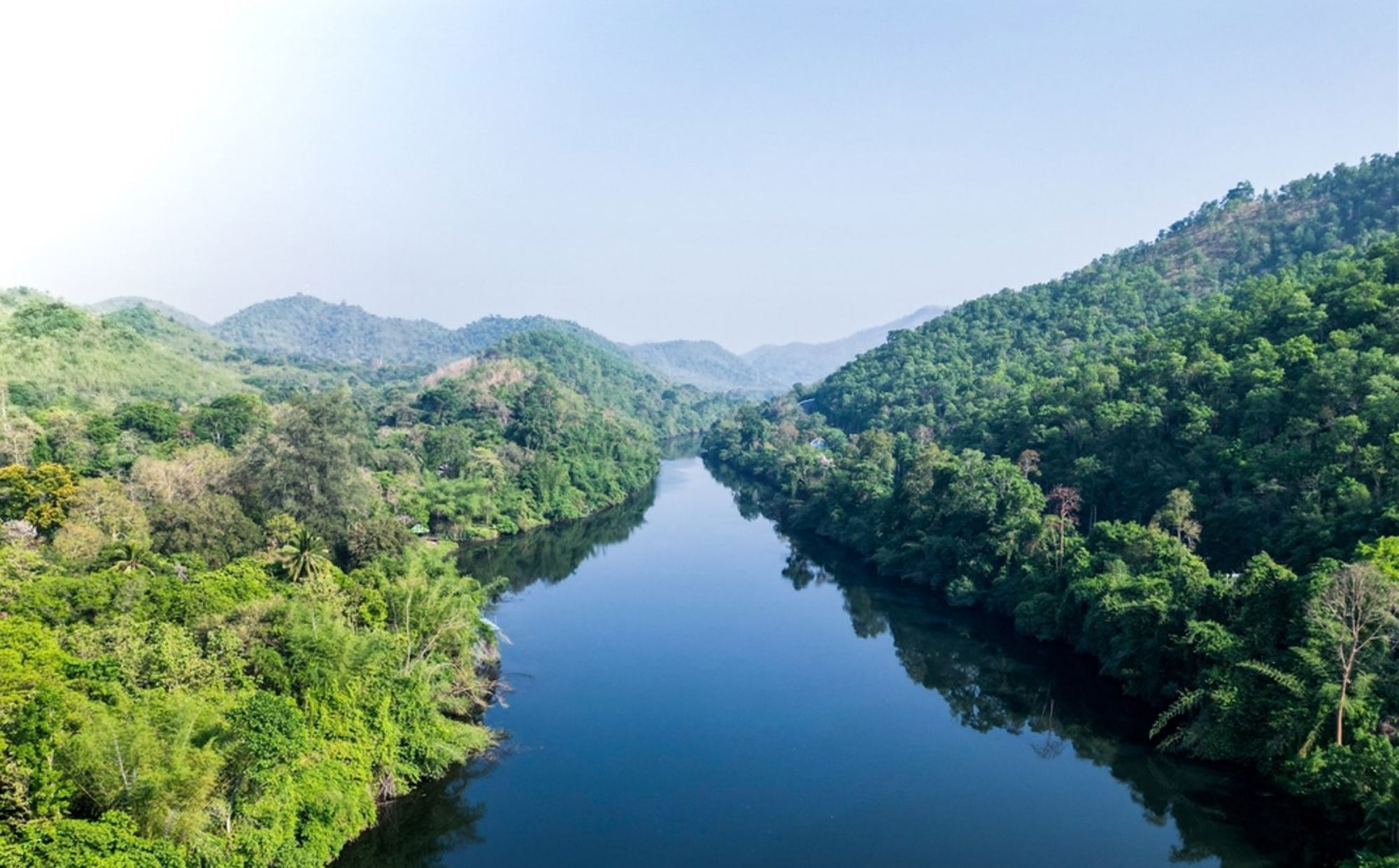 Rivier tussen groene, beboste heuvels in Thailand, gezien vanuit de lucht.