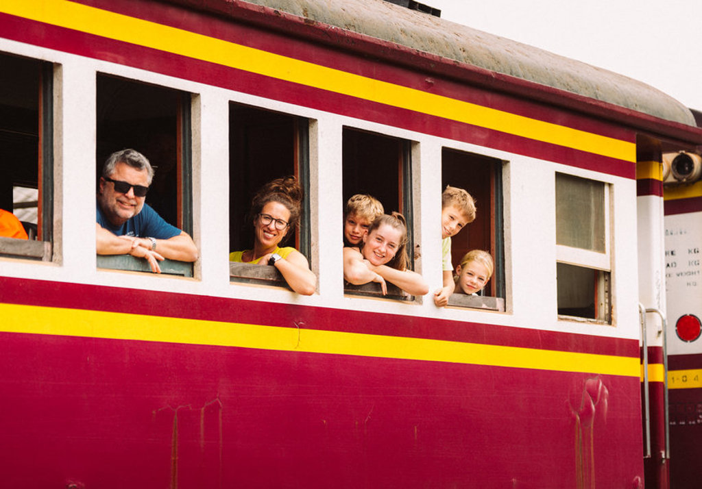 Gezin kijkt uit het raam van een kleurrijke trein tijdens familiereis Thailand Noord en Zuid.