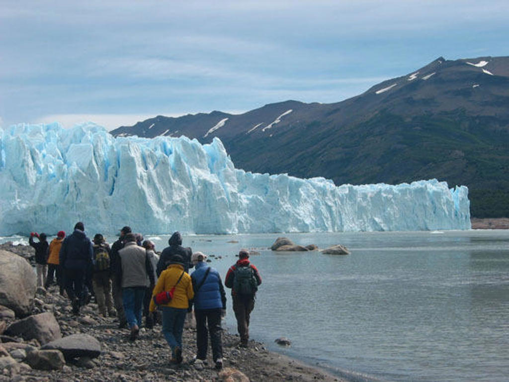 Wandelaars langs een krakende gletsjer aan een bergmeer in Patagonië tijdens groepsrondreis Patagonië en Paaseiland.