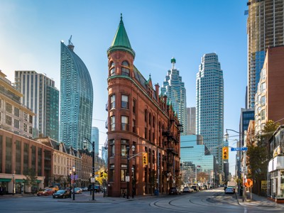 Historisch Flatiron-gebouw in Toronto met moderne wolkenkrabbers op de achtergrond.