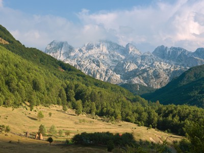 Groene vallei met bossen en ruige bergtoppen langs de Route Zuid-Oost Europa.