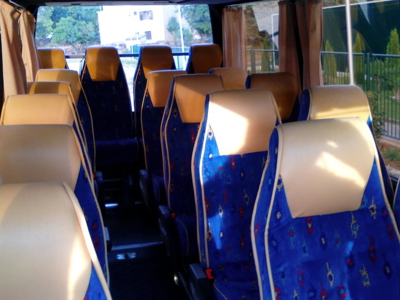 Interieur van een touringcar met blauwe stoelen voor vervoer tijdens een Balkanreis.